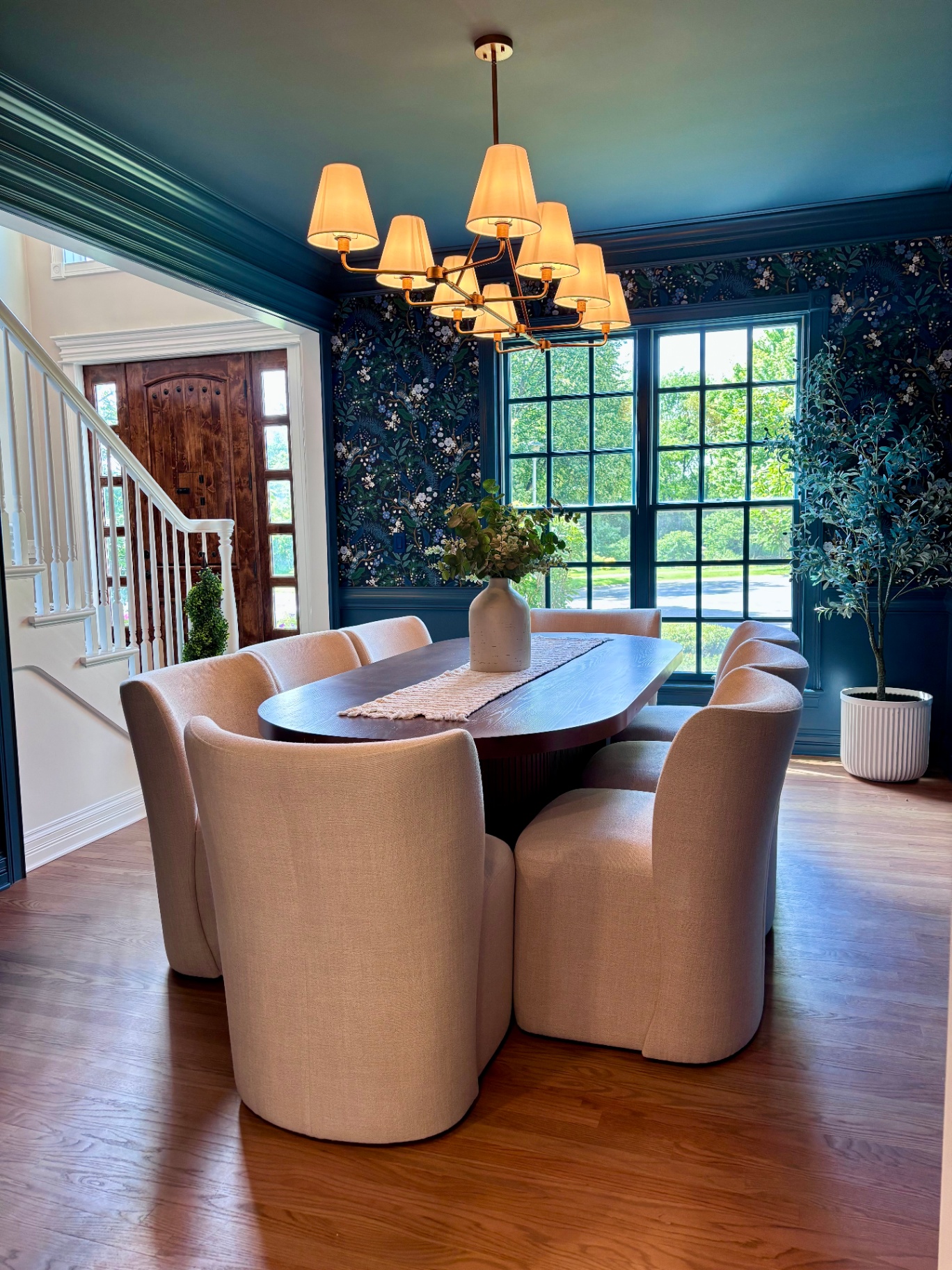 Formal dining room with deep blue wallpaper and brass chandelier