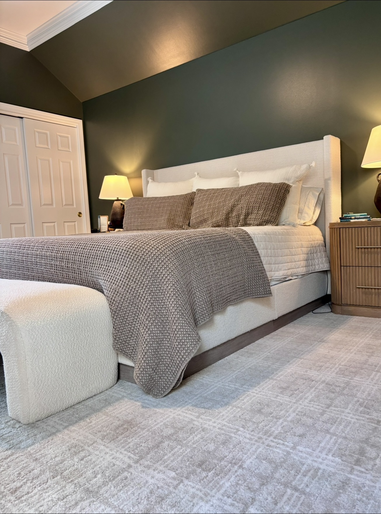 Master bedroom with deep green accent wall and upholstered bed