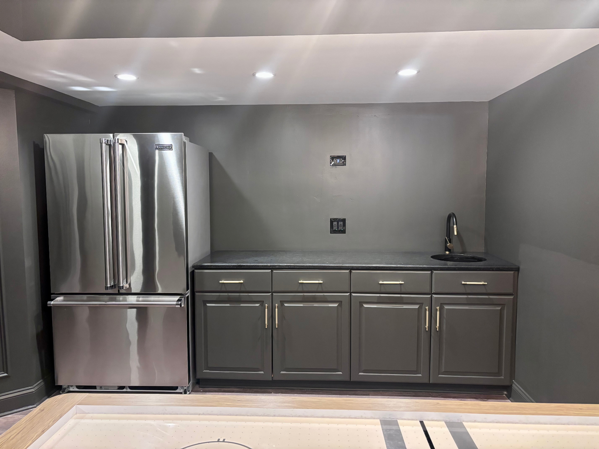 Custom basement bar with stainless fridge and stone countertop