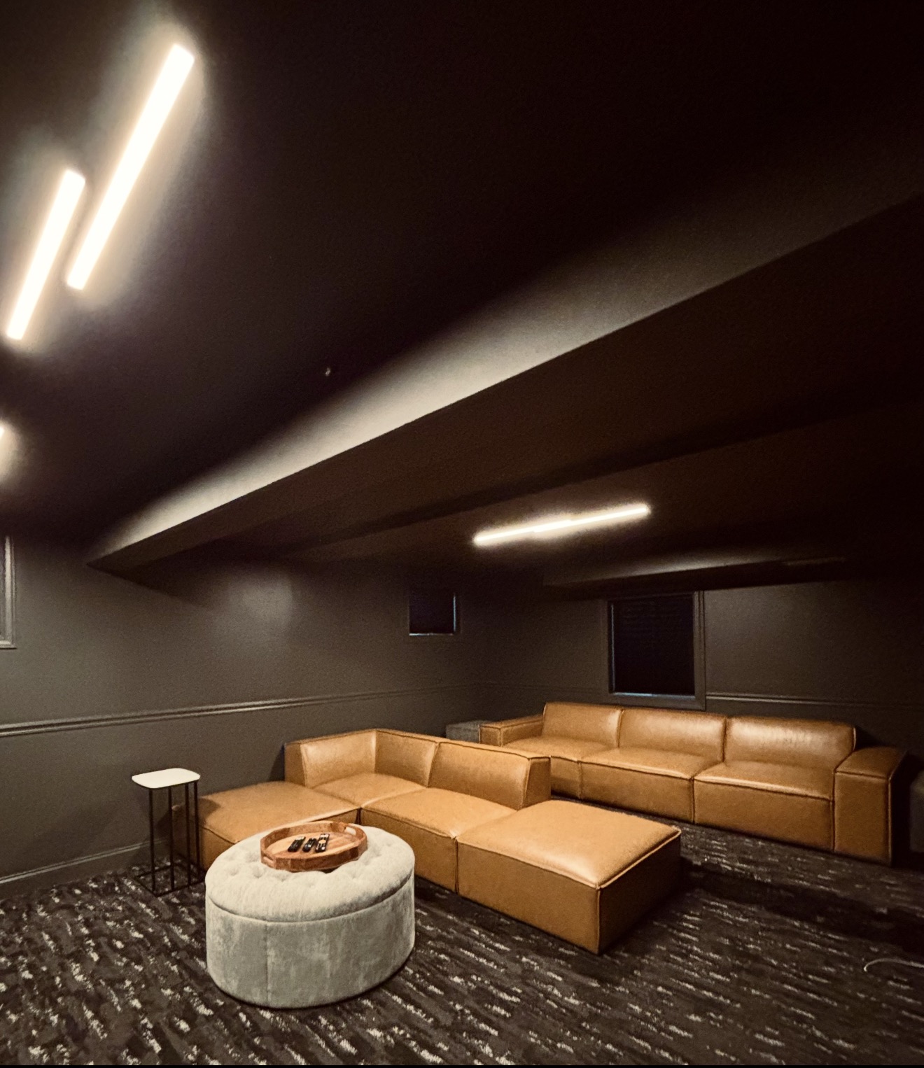 Home theater room with tan leather sectional and accent lighting