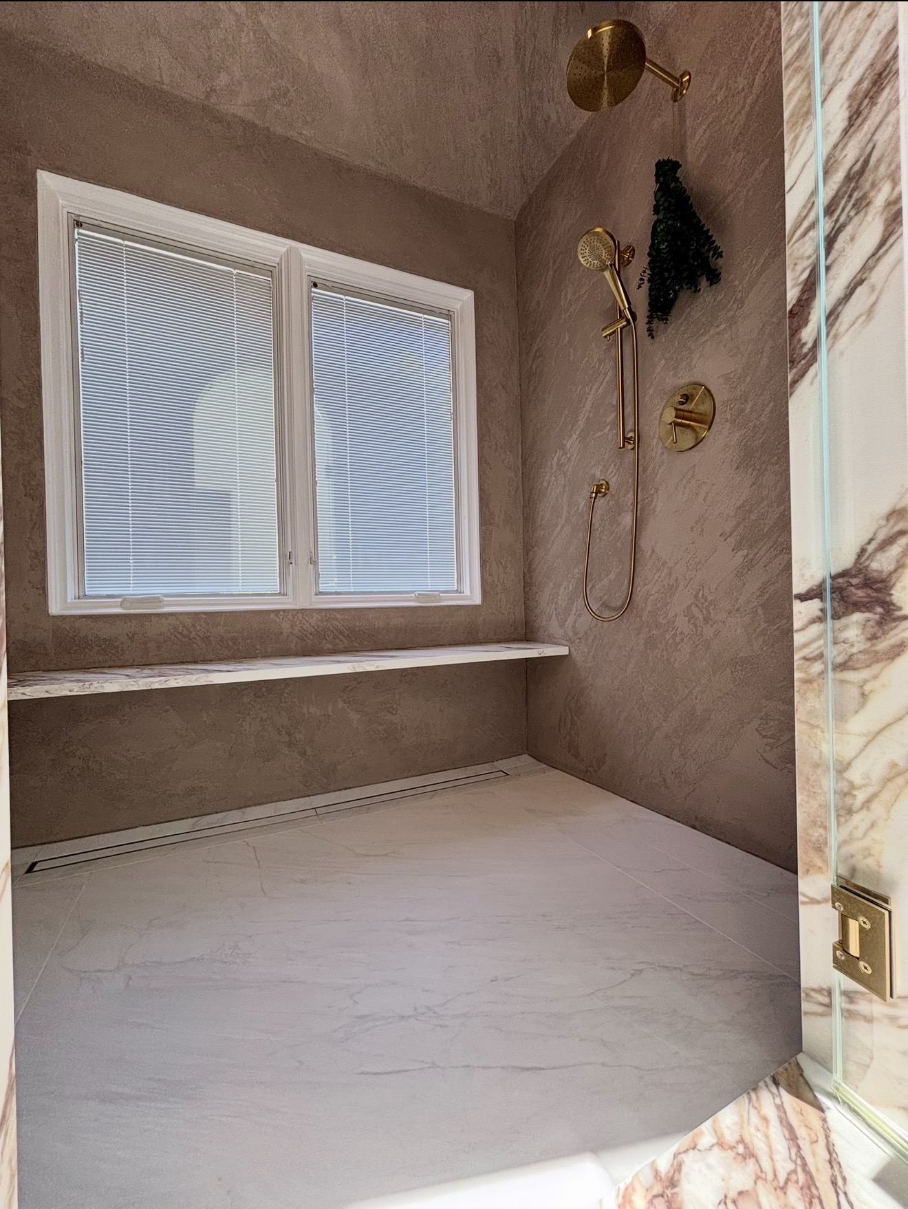 Walk-in shower with venetian plaster walls and brass fixtures