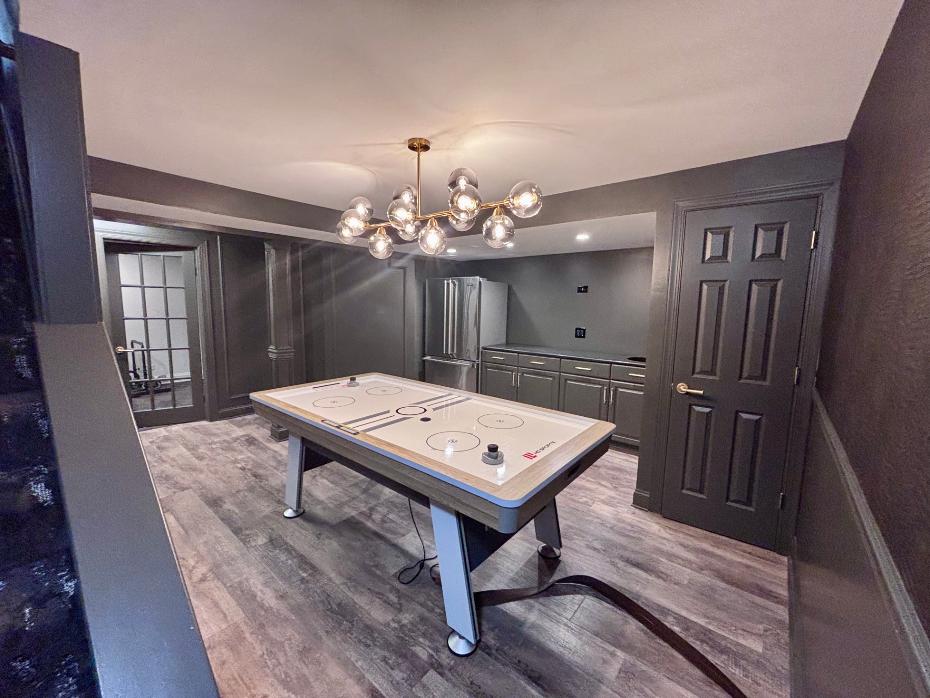 Basement game room with modern chandelier and air hockey