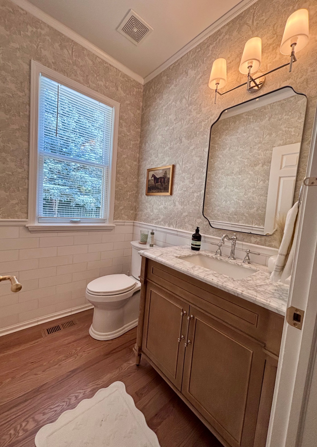 Powder room with equestrian toile wallpaper and marble vanity