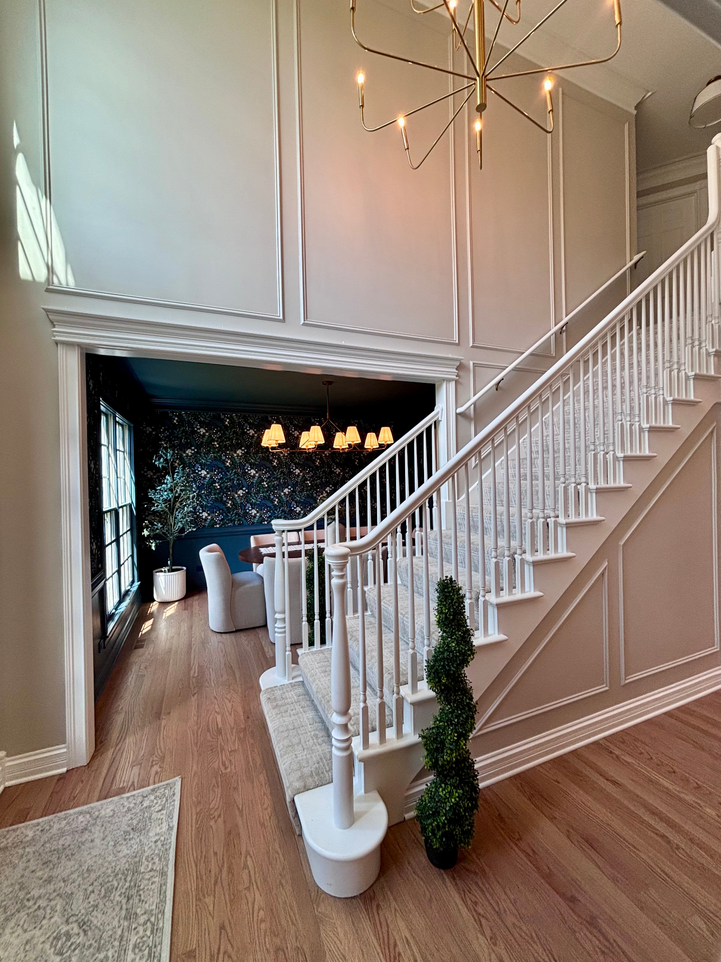 Foyer looking into dining room with dark floral wallpaper