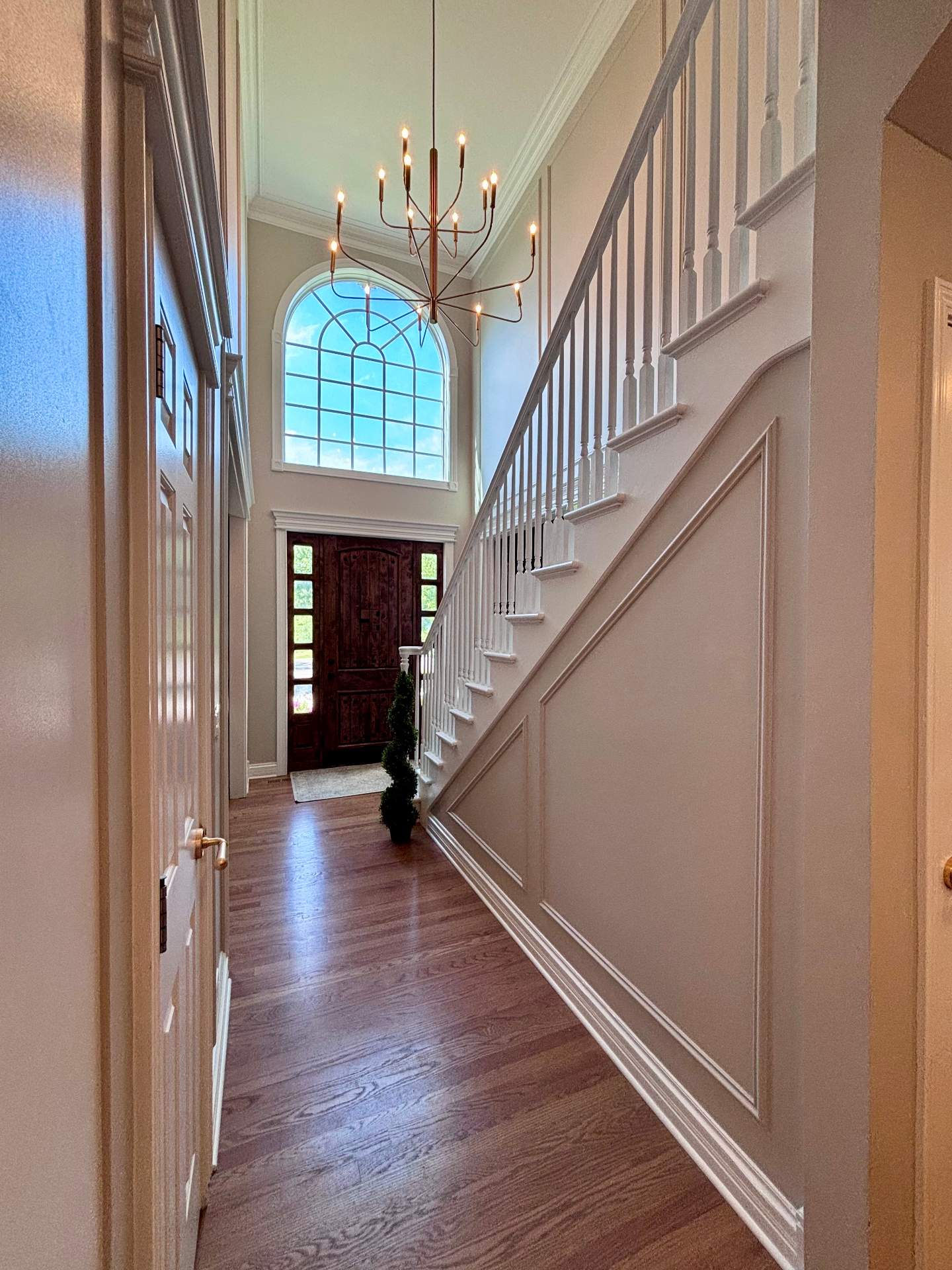 Two-story foyer with brass chandelier and arched window