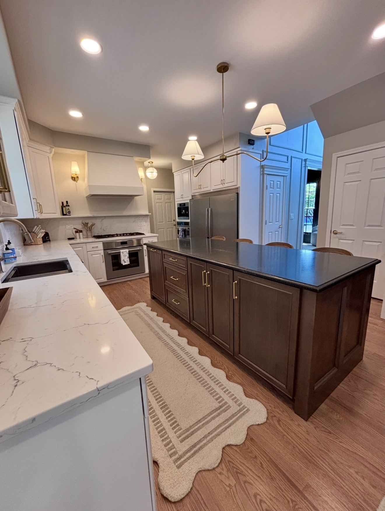 Open kitchen with dark island, brass hardware and marble counters
